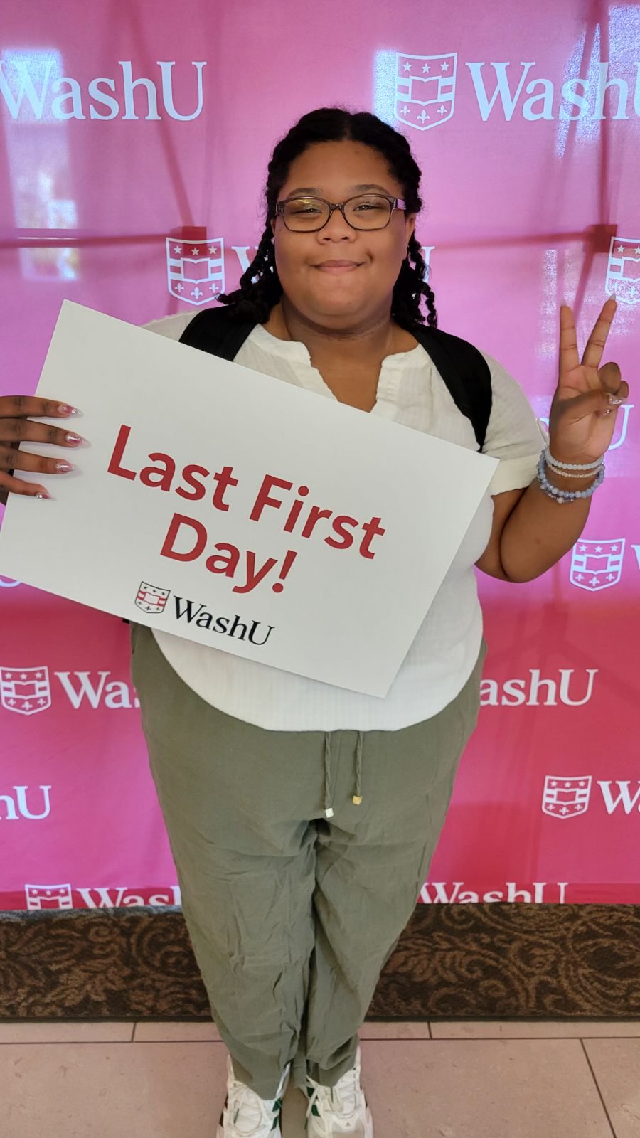 Proud student stands with sign that reads "Last first day!"
